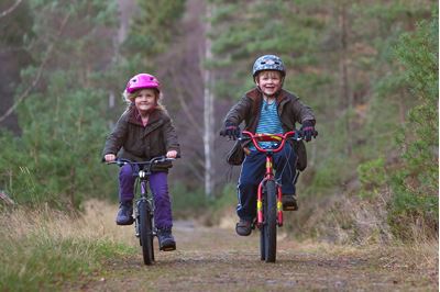 Children riding bikes, Inshriach Forest, Cairngorms National Park, Scotland. 